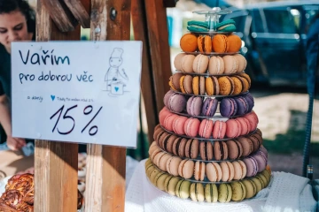 Stánek s věží barevných makronek a cedulí „Vařím pro dobrou věc" na festivalu.
