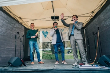 Moderátoři na pódiu během slavnostního zahájení festivalu, jeden má zvednutou ruku.