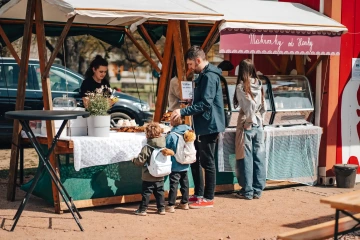 Rodina s malými dětmi si vybírá občerstvení u stánku se sladkostmi.