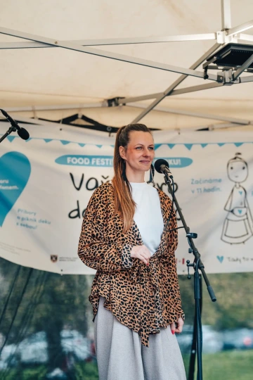 Zpěvačka v leopardím kabátu usmívající se na pódiu během festivalového programu.